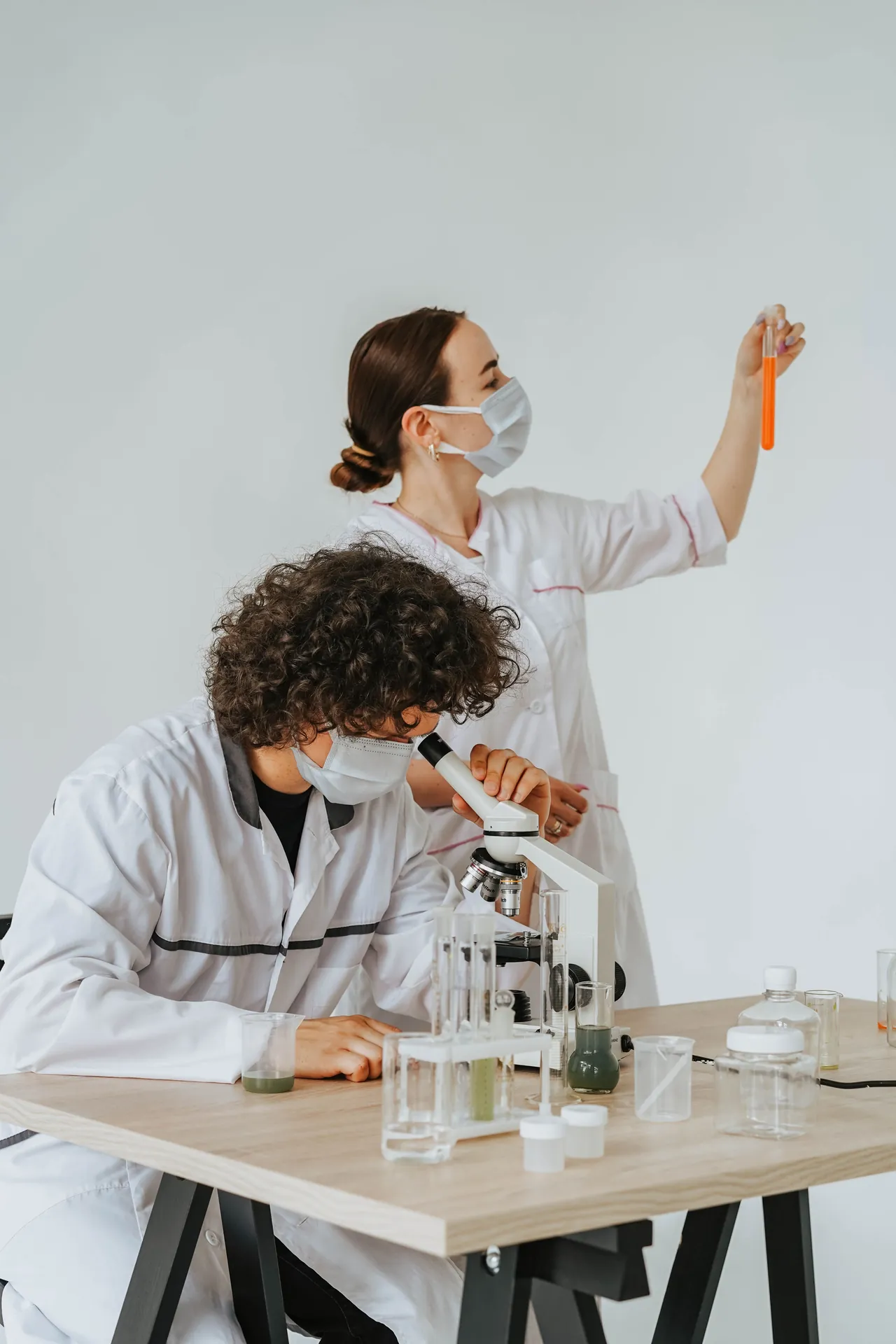 Two young researchers working with a microscope and a test tube in a laboratory