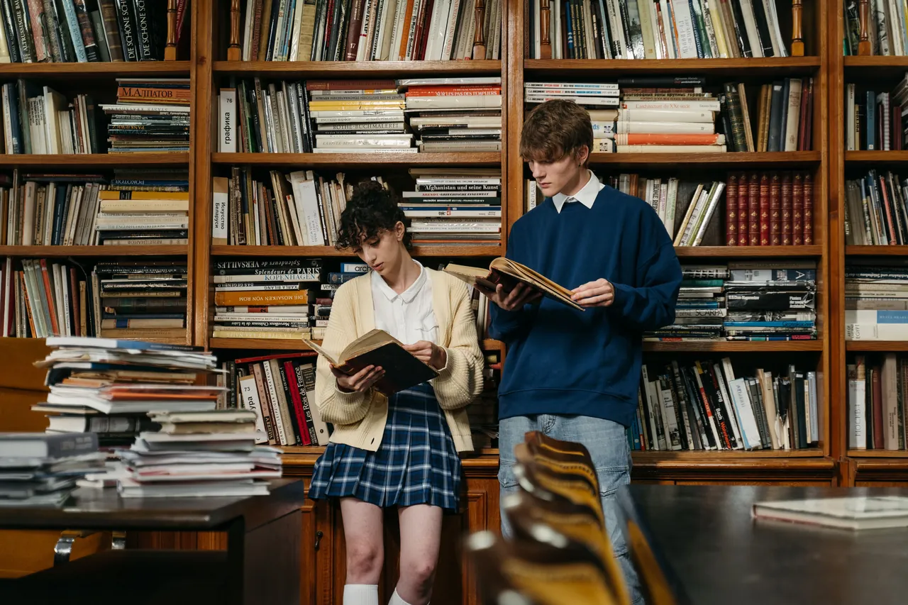 Two students reading books in a library